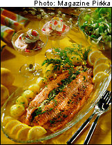 A piece of baked salmon on a glass dish surrounded with slices of lemon.