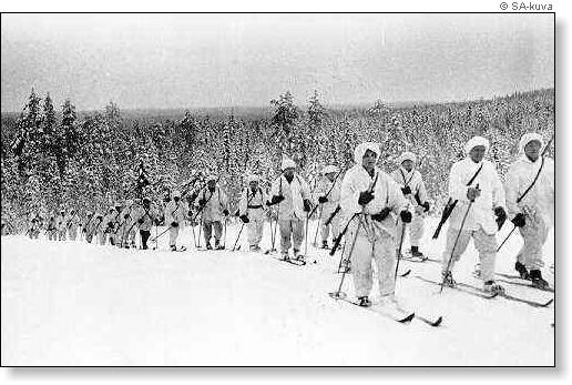 A black-and-white photo of Finnish ski troops in their white gear skiing in a forest.