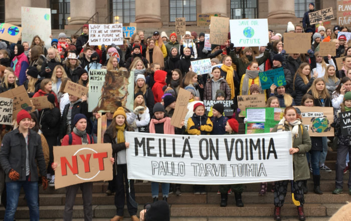 A large crowd of young people hold signs at a climate demonstration.