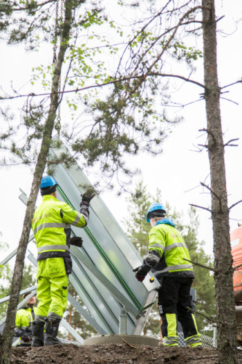 Workers install up a solar panel beside a school.