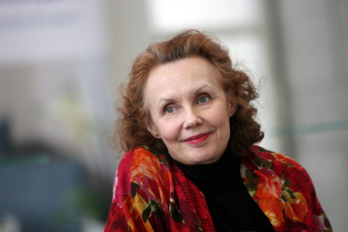 A woman with a slight smile on her face gazes past the camera.