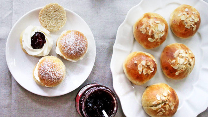 Two plates of buns are visible, one set with jam filling and one set with sliced almonds on top.