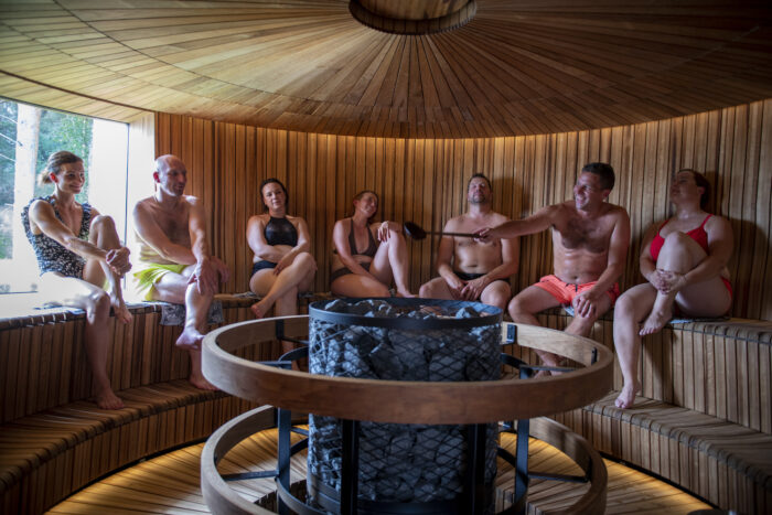 Uma fileira de pessoas está sentada em um banco de uma sauna circular.