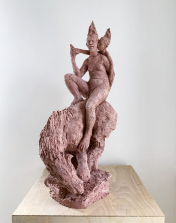 A sculpture shows two human-like figures on the back of a horse-like animal.
