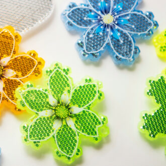 Several flat, six-pointed pieces of plastic with various patterns and colours on them are lying on a table.