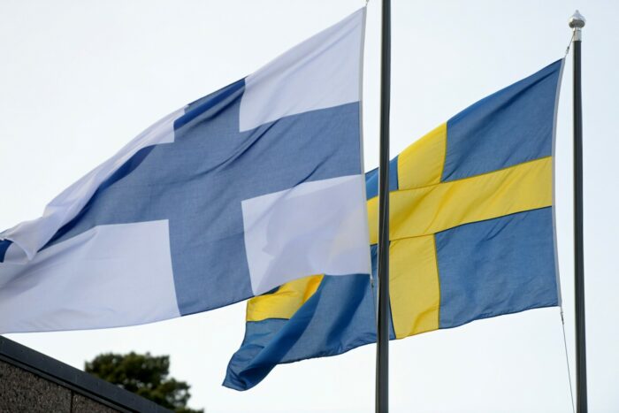 Les drapeaux finlandais et suédois hissés sur leur mât respectif flottent côte à côte au vent.
